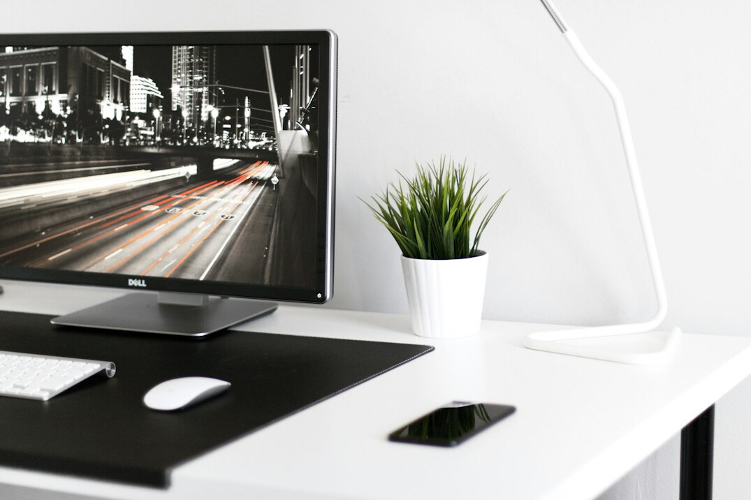 Laptop displaying charts and graphs on a wooden desk with notebook and pen
